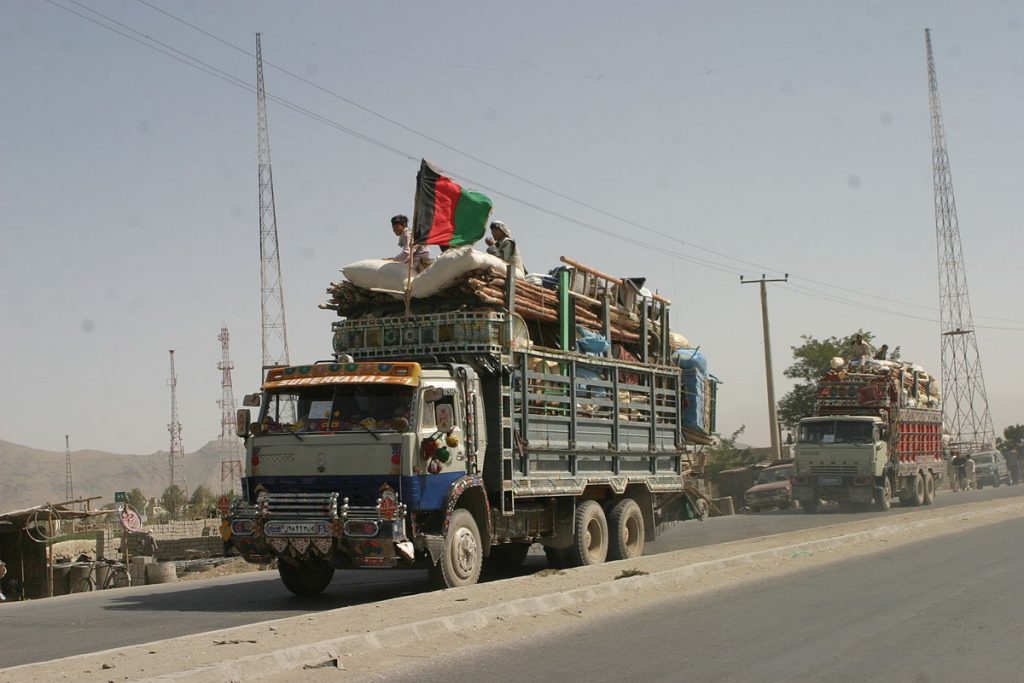 Afghans who were repatriated are arriving to Afghanistan in a truck with an Afghan flag on it